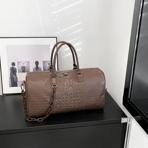 Detailed view of large brown crocodile-embossed travel bag in minimalist home decor