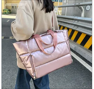 Vista lateral detallada de la bolsa de viaje acolchada rosa metalizado con textura de plumón