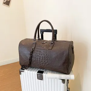 Detailed macro view of brown crocodile pattern faux leather travel bag on a suitcase