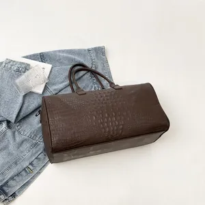 Macro view of brown crocodile texture on a large capacity travel bag with lifestyle props