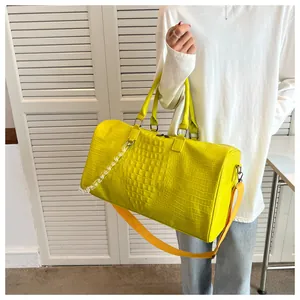 Detailed shot of a model carrying a vibrant yellow crocodile texture travel handbag
