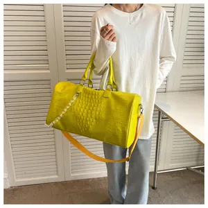 Macro detail of a bright lime yellow crocodile pattern duffel bag with a clear chain