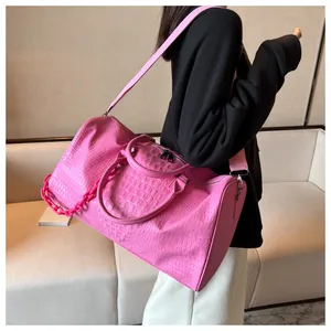 Detail of large pink crocodile embossed faux leather travel bag with shoulder strap