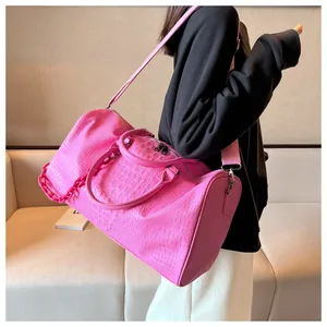 Vibrant pink crocodile embossed travel duffel bag carried by model for weekend getaway
