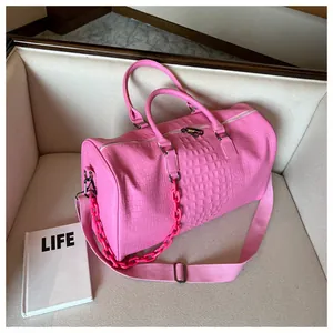 Stylish pink crocodile textured large capacity travel bag with chain detail on a sofa.