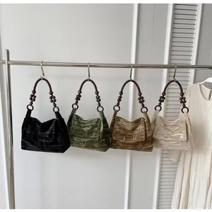 Cuatro elegantes bolsos de hombro de terciopelo retro con asas de cuentas de madera rústica.