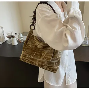 Detalle de bolso de hombro de terciopelo vintage con estampado de bambú y correa de cuentas.