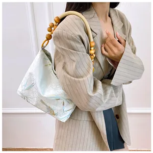 Dettaglio di borsa a spalla floreale stile cinese con elegante tracolla in legno.