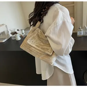 Primer plano de un bolso de hombro vintage con cuentas de estilo chino y camisa blanca.