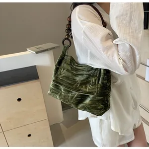 Primer plano de bolso de hombro de terciopelo verde con motivos de bambú y cuentas de madera