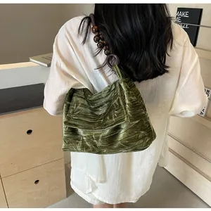 Detalle de bolso de hombro de terciopelo verde con estampado retro y correa de cuentas