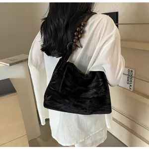 Detalle de bolso de hombro de terciopelo negro con estampado de bambú y asa de cuentas