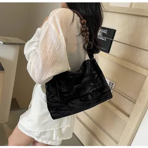 Detalle de un bolso de hombro jacquard negro con un diseño de correa de cuentas de madera retro