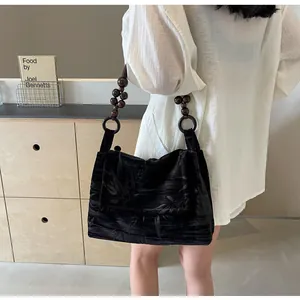 Detalle de un bolso de hombro de terciopelo negro con cuentas y estampado de bambú