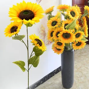 Detailed view of vibrant yellow artificial sunflowers in a tall black floor vase