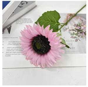 Detailansicht einer rosa künstlichen Sonnenblume mit grünen Blättern für die Deko