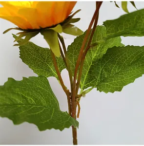 Detalle de primer plano del tallo y las hojas verdes de un girasol artificial.