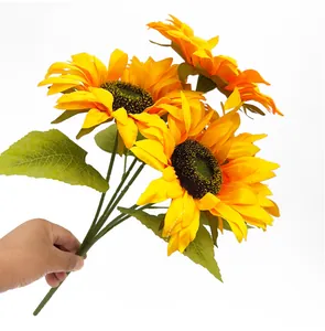 Hand met een boeket van vijf realistische gele kunstzonnebloemen voor decoratie.
