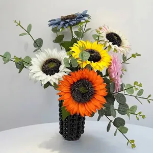 Lebhafter künstlicher Sonnenblumenstrauß mit Eukalyptus in einer schwarzen Vase