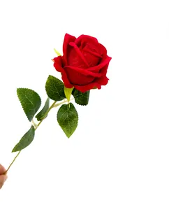 Primo piano dettagliato di una rosa artificiale in velluto rosso con foglie verdi sullo stelo