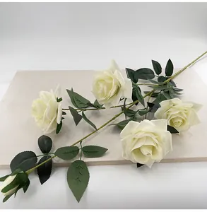 Detailed view of white velvet artificial roses with natural petal texture and green leaves.