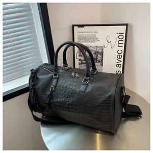 Detailed view of a large black crocodile-embossed leather travel bag on a modern table
