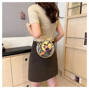 Detail of transparent round crossbody bag with cute cartoon witch design and gold chain.