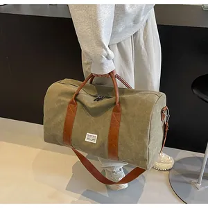 Olivegrüne Segeltuch-Reisetasche mit braunen Ledergriffen und verstellbarem Gurt.