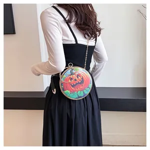 Close-up detail of a round funny pumpkin chain crossbody bag shown on a model outfit