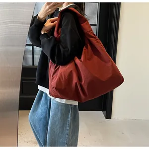 Bolso bandolera grande de lona rojo oscuro mostrado con una modelo en interiores