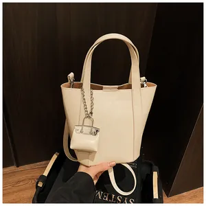 Nahaufnahme einer minimalistischen cremefarbenen Beuteltasche mit passendem Mini-Taschenanhänger