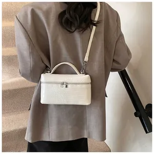 Elegant white crocodile pattern box crossbody bag worn by a model in a brown blazer.