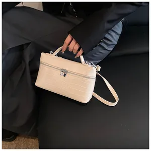 Close-up of beige crocodile pattern box bag with top handle and shoulder strap