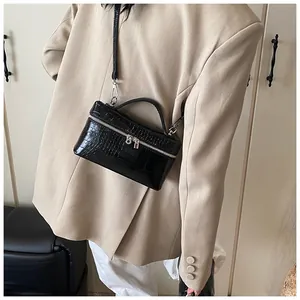 Macro view of black croc-embossed box bag worn over a beige blazer for styling detail