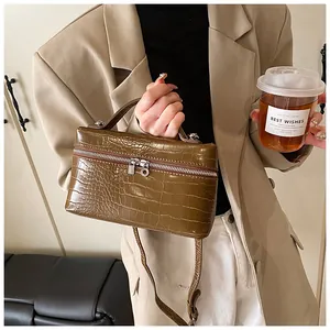 Elegant brown crocodile embossed box handbag held by a model in a stylish beige blazer.
