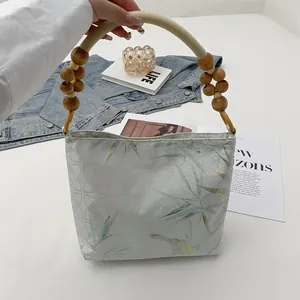 Vista dettagliata della stampa floreale e del manico in legno di questa borsa rétro