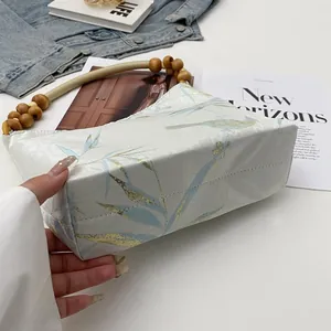 Vista dettagliata della borsa a mano con stampa retrò e manico decorativo in legno