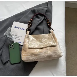 Vista detallada de un bolso de terciopelo estampado con una asa de cuentas de madera.