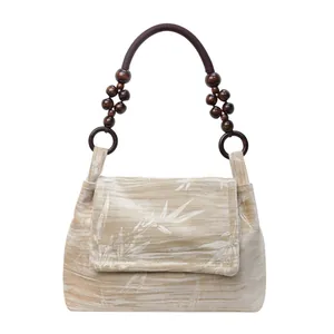 Detalle del bolso retro de estilo chino con estampados de bambú y asa de cuentas de madera.