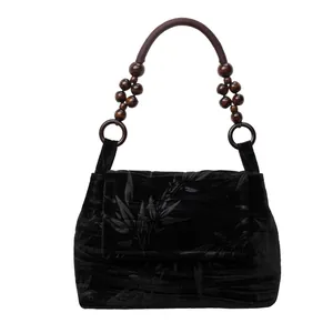 Detalle de bolso de terciopelo negro con asa de cuentas de madera en estilo chino