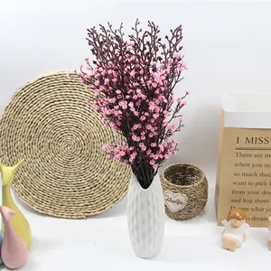 Fiori di gypsophila rosa artificiali in un vaso di ceramica bianca per casa.