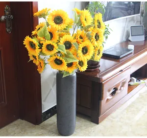 Primer plano detallado de girasoles artificiales vibrantes en un jarrón gris para decorar.