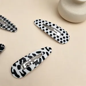 Detailed macro view of black and white patterned BB hair clips on beige surface.