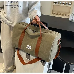 Detailansicht der großen grünen Canvas-Reisetasche mit braunen Lederriemen auf einem Koffer