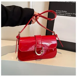 Detail van de rode lakleren handtas met een opvallende goudkleurige D-vormige gesp.