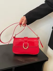 Elegante levendige rode laklederen handtas met de hand vastgehouden tegen achtergrond