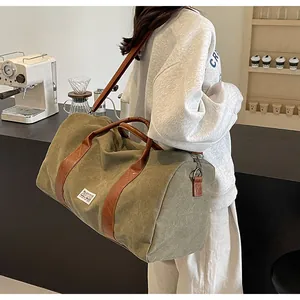 Detailansicht einer grünen Reisetasche aus Segeltuch mit braunen Trägern an der Schulter