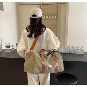 Weibliches Model trägt eine grüne Reisetasche aus Canvas mit braunen Lederakzenten