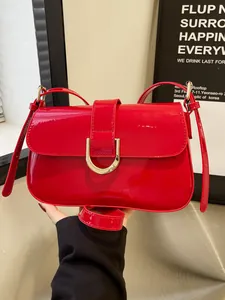 Detail van een rode lakleren handtas met een gouden U-vormige metalen gesp