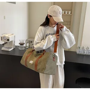 Große Reisetasche aus olivfarbenem Canvas, getragen von einem Model in einem Café-Set